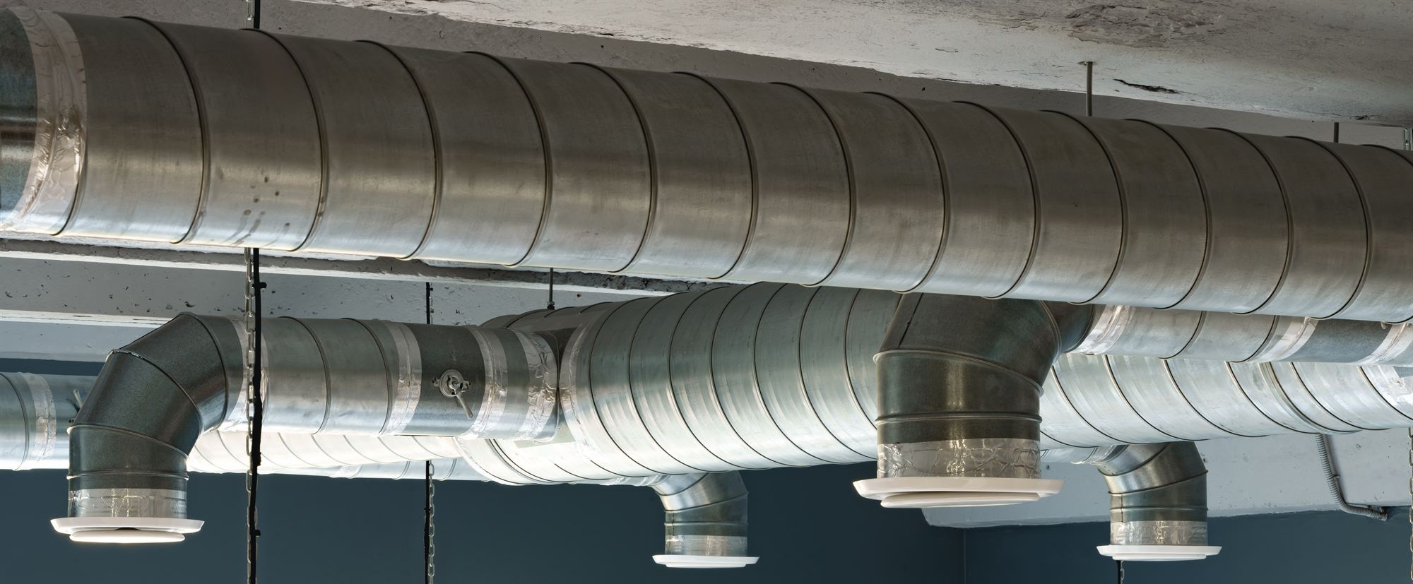 Galvanised spiral ductwork and ceiling diffusers installed across a commercial ceiling